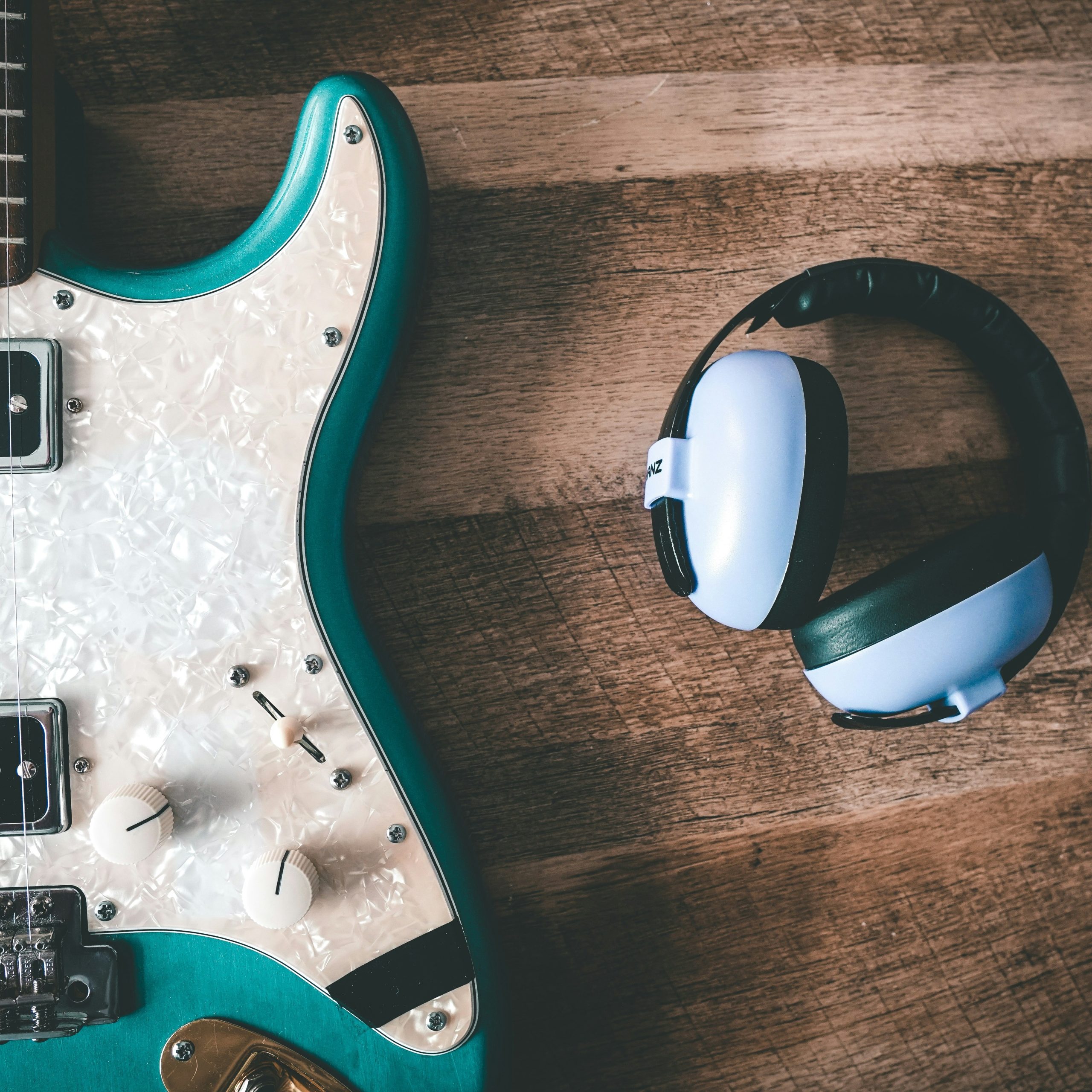 Guitare électrique turquoise et casque audio sur table en bois